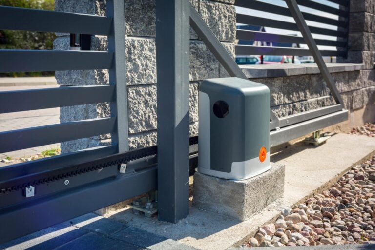 Automatic gate opener mounted on a concrete block beside a blue, horizontally slatted metal gate.