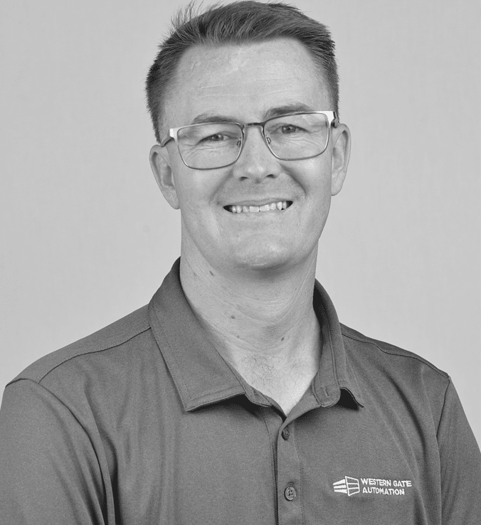 Smiling man wearing glasses and a polo shirt with a logo on the chest.