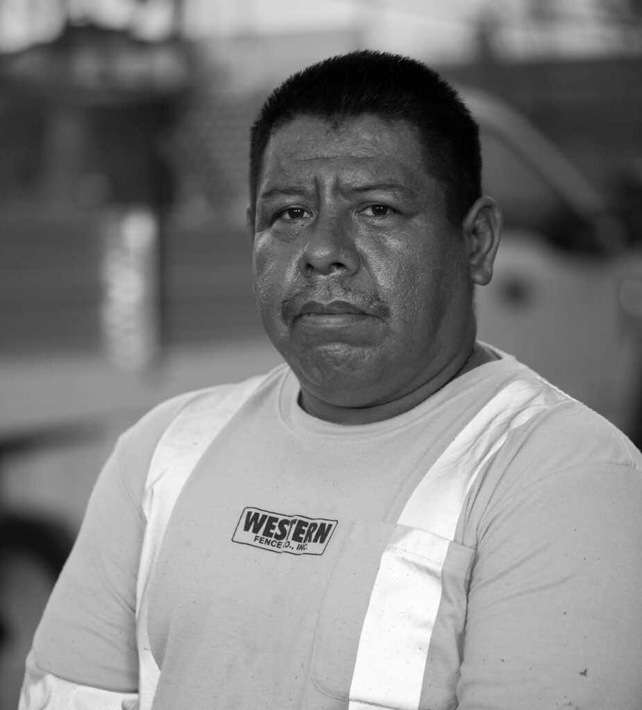 A man with a stern expression wearing a light shirt with white suspenders and a patch reading Western on his chest.