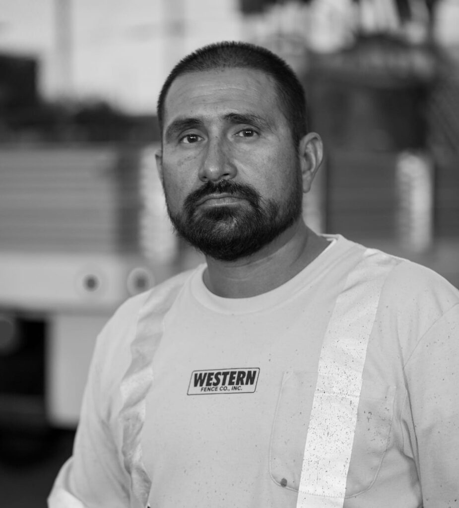Portrait of a bearded man wearing a light shirt with a Western logo in a workshop.